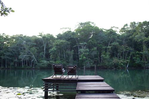 two chairs sitting on a dock in the middle of a lake at El Hotelito Perdido in Rio Dulce