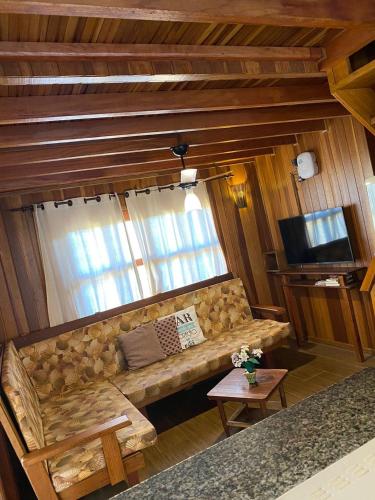a living room with a couch and a television at Chalé Paraíso com piscina privativa em Brotas SP in Brotas
