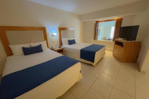 een hotelkamer met twee bedden en een televisie bij Beach and Pool Access! in Puerto Vallarta