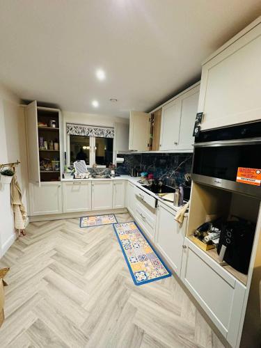 a kitchen with white cabinets and a wooden floor at Cosy and beautiful home Vegetarians only in Dublin