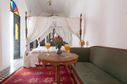 1 Schlafzimmer mit einem Bett mit einem Tisch und 2 Gläsern Orangensaft in der Unterkunft Riad Ifoulki in Marrakesch