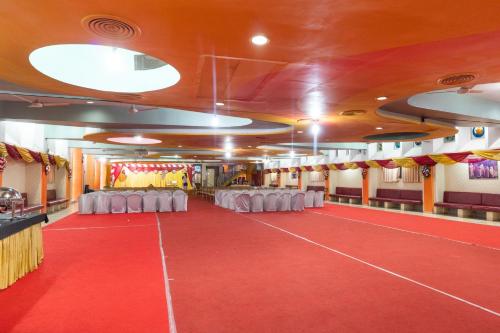 a room with a red floor and white tables and chairs at Hotel O Shivam in Vadodara