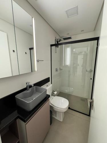 a bathroom with a sink and a toilet and a mirror at Apartamento Edifício Vista Mare in Torres