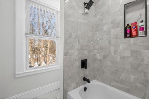 a bathroom with a white tub and a window at Royal Flush-6 King Beds-18 Mi To Mohegan in Norwich