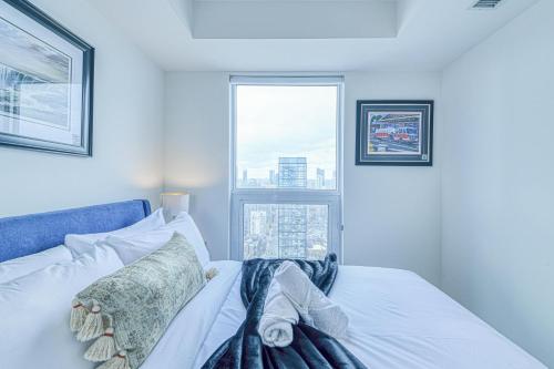 a bedroom with a white bed with a window at RivetStays - The Jarvis in Toronto
