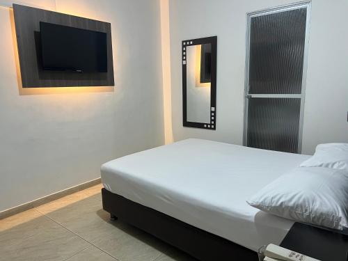 a bedroom with a bed and a flat screen tv at Hotel Marialu in Ocaña