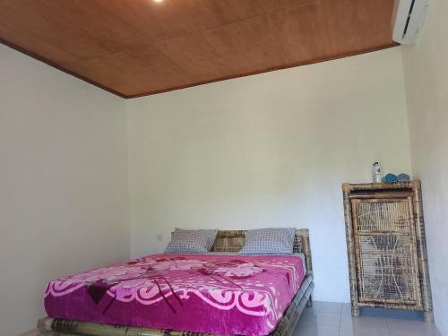 a bedroom with a pink bed and a wooden ceiling at Rasta Homestay Ekas Bay in Pulau Gilkaliantan