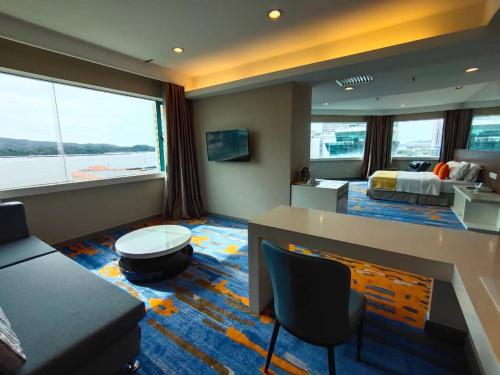 a hotel room with a bed and a living room at Hotel Capital Kota Kinabalu in Kota Kinabalu