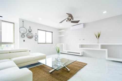 a white living room with a white couch and a glass table at Palmarena Rooms & Residences - Long Stay Comfort with Parking, Sauna, Gym & Pool - Steps from 5th Avenue in Playa del Carmen