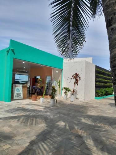 a green building with potted plants in front of it at Aconchego in Praia Grande