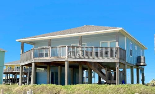 a large blue house with a deck on the beach at Sunburn Alley home in Caplen