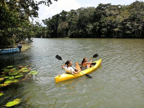two girls in a yellow kayak on a lake at El Hotelito Perdido in Rio Dulce