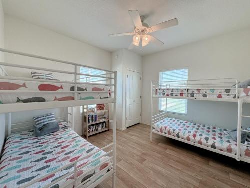a bedroom with two bunk beds and a ceiling fan at Sunburn Alley home in Caplen