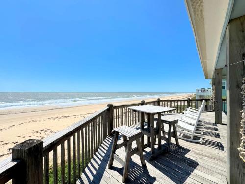 a table and chairs on a balcony overlooking the beach at Sunburn Alley home in Caplen