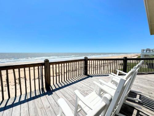 two white chairs sitting on a deck overlooking the beach at Sunburn Alley home in Caplen