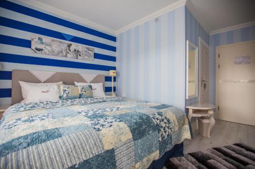 a bedroom with a bed with blue and white stripes at Hotel Ottaviano in Świnoujście