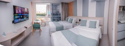 a hotel room with two beds and a tv at Porto Horizonte Suite 735 in Santa Marta
