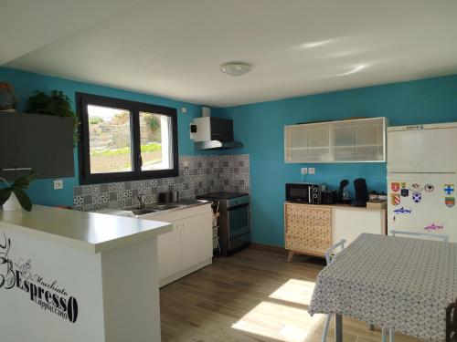 - une cuisine avec des murs bleus, une table et un réfrigérateur dans l'établissement Guest House Le Citronnier, à Roullens