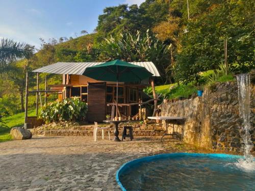 a house with an umbrella next to a pool at Casa Yantra La Lola in Pance