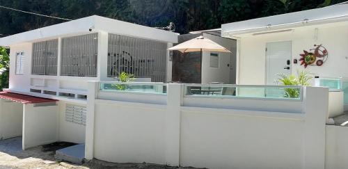 a white building with a fence and an umbrella at New ! Casa de Campo del Río Planta in Arecibo