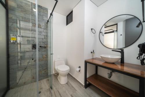 a bathroom with a toilet and a sink and a mirror at Epic Suites x Ahead in Pereira
