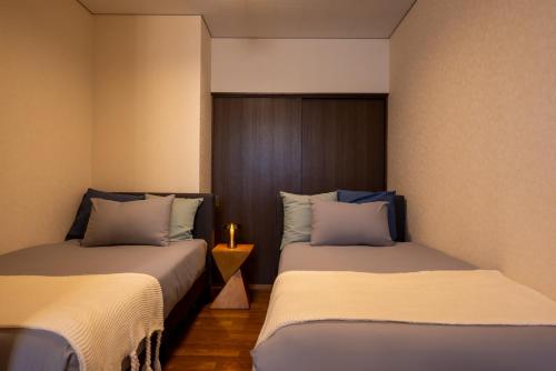 two beds sitting next to each other in a room at BREEZE furano Annex205 in Furano