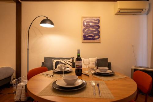 a dining room table with a bottle of wine and glasses at BREEZE furano Annex205 in Furano