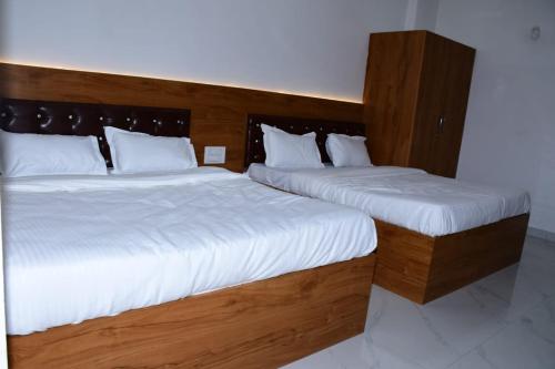 two beds in a hotel room with white sheets at Hotel Deep Nisha in Khātu