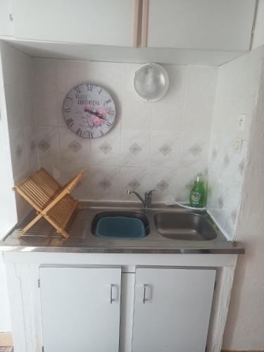 une cuisine avec un évier et une horloge murale dans l'établissement Maison de Polly, à Saint-Gaultier
