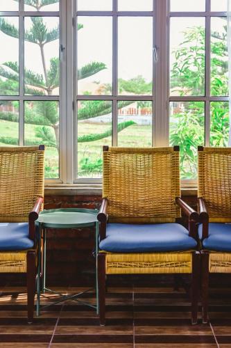 three chairs and a table in front of a window at Mimi's Pine Meadow - Where it Nourishes Our Souls in Pulau Langkawi