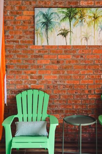 a green chair sitting next to a brick wall with a painting at Mimi's Pine Meadow - Where it Nourishes Our Souls in Pulau Langkawi