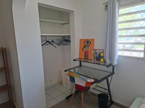 a desk in a room with a chair and a window at Logement intéressant in Kourou