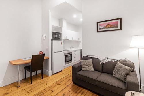 a living room with a couch and a table and a kitchen at Flinders Lane City Apartment Superior Studio in Melbourne