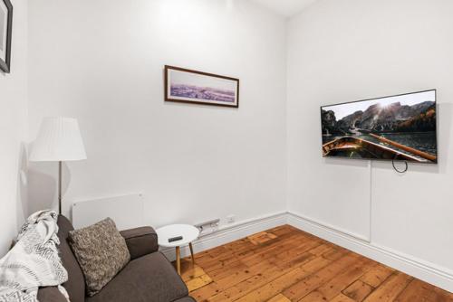 a living room with a couch and a tv on the wall at Flinders Lane City Apartment Superior Studio in Melbourne