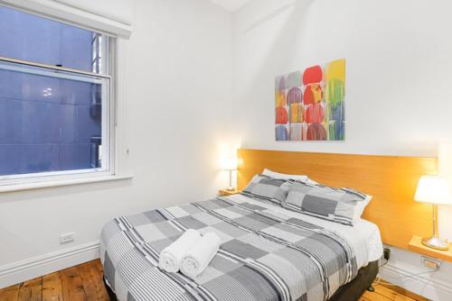 a bedroom with a bed with two lamps and a window at Flinders Lane City Apartment Superior Studio in Melbourne