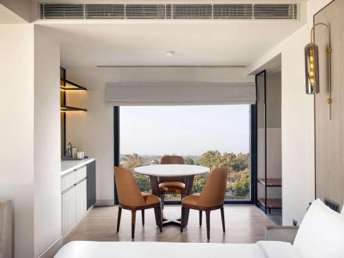 a dining room with a table and chairs and a window at Mercure Chandigarh Tribune Chowk in Chandīgarh