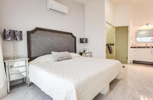 a bedroom with a large white bed and a bathroom at The Residences by Morgan in Cabo San Lucas