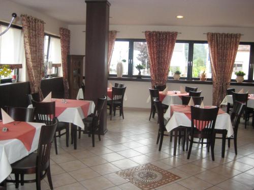 a dining room with tables and chairs and windows at Bliestal Hotel in Blieskastel