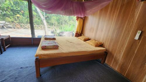 a small bed in a room with a window at Dong Que Homestay-Tours-Motorbike, Car rental, Hiking in Ha Giang