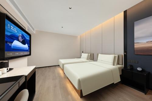 a bedroom with a white bed and a flat screen tv at Atour Hotel Shanghai Dapu Bridge ASE Center in Shanghai