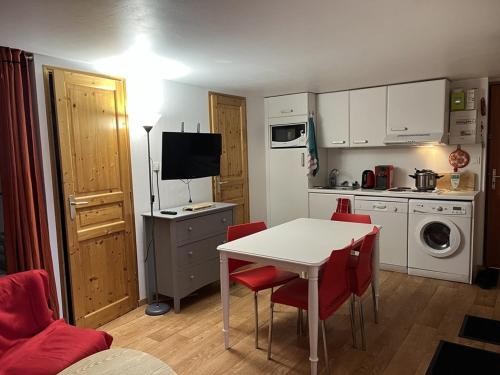 eine kleine Küche mit einem Tisch und roten Stühlen in der Unterkunft Studio central au Lioran avec terrasse et parking - FR-1-787-125 in Laveissière