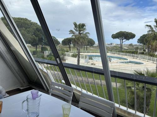Cette chambre dispose d'une table et offre une vue sur la piscine. dans l'établissement Studio climatisé avec terrasse, 4 couchages, proche plage et commerces - FR-1-250-307, au Grau-du-Roi