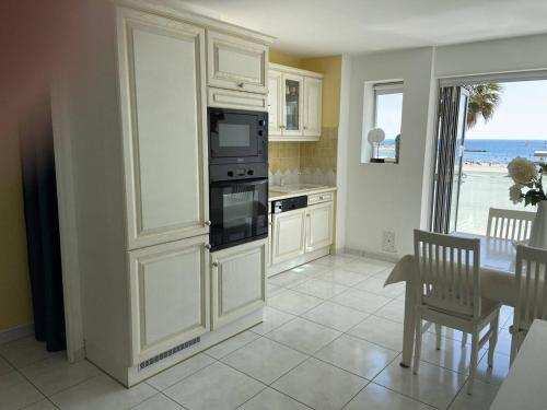 une cuisine avec une cuisinière et un micro-ondes dans l'établissement Deux-Pièces Neuf Climatisé Face Mer à Canet-Plage - FR-1-750-76, à Canet