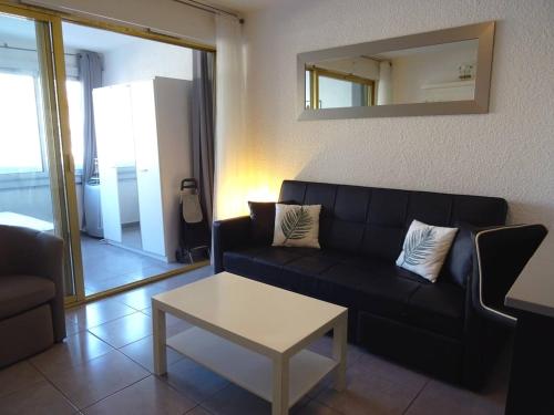 un salon avec un canapé noir et une table dans l'établissement Studio central avec loggia et wifi - FR-1-833-21, à Canet