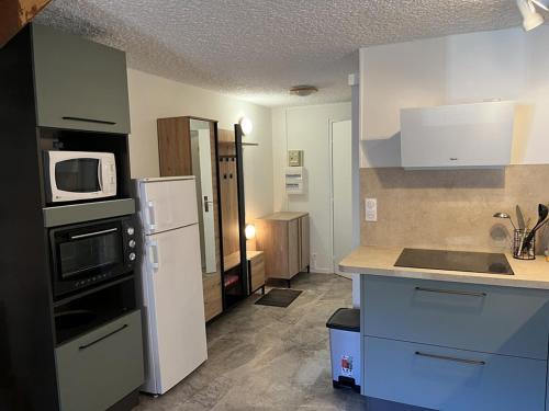 La cuisine est équipée d'un réfrigérateur blanc et d'un four micro-ondes. dans l'établissement Appartement duplex 6/8 pers, centre station, Le Lioran - FR-1-787-124, à Laveissière
