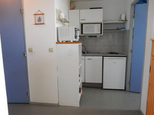 une petite cuisine avec un réfrigérateur et un micro-ondes dans l'établissement Appartement 5 pers avec piscine en bord de mer - FR-1-750-77, à Canet