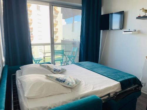 un lit dans une chambre avec une grande fenêtre dans l'établissement Studio avec Terrasse près du Port d'Arcachon, à Arcachon