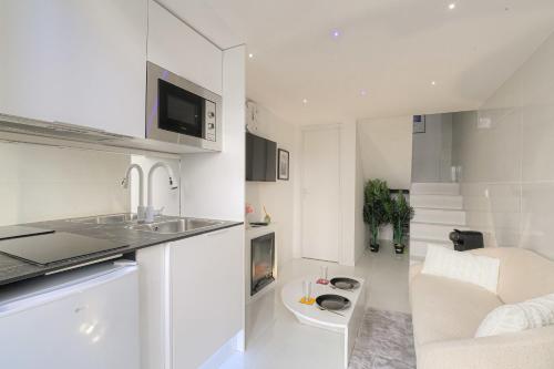- une cuisine blanche avec un évier et un canapé dans l'établissement Cosy et Chaleureux duplex Brotteaux - Masséna, à Lyon