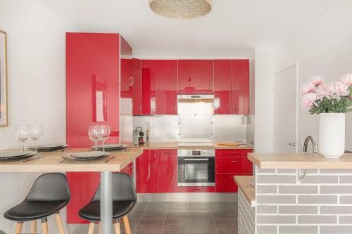 une cuisine rouge avec des armoires rouges et des chaises noires dans l'établissement Cosy et Calme 7min métro Garibaldi, à Lyon