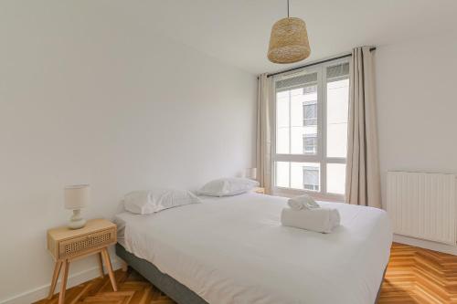 un lit blanc dans une chambre avec une fenêtre dans l'établissement Cosy et Calme 7min métro Garibaldi, à Lyon